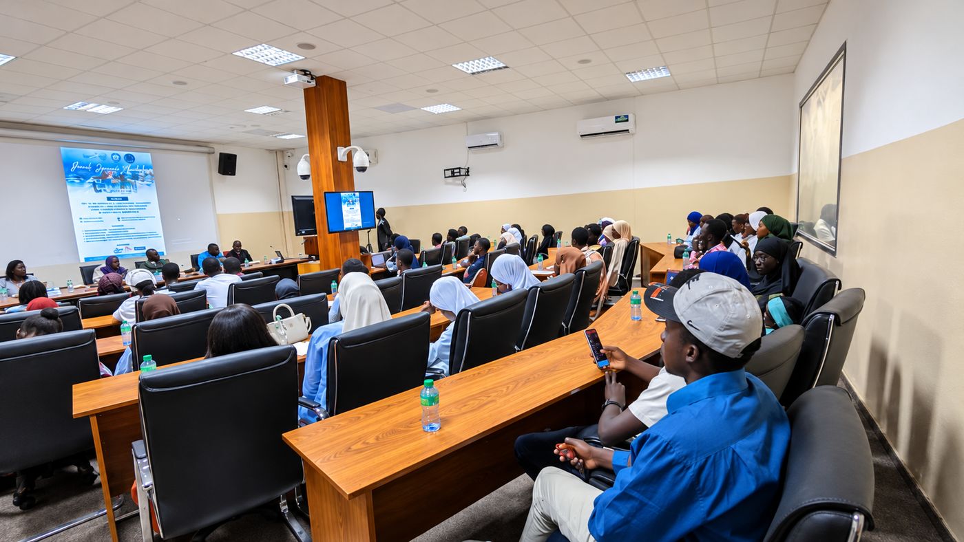 An audience seated in a lecture hall facing a projected presentation