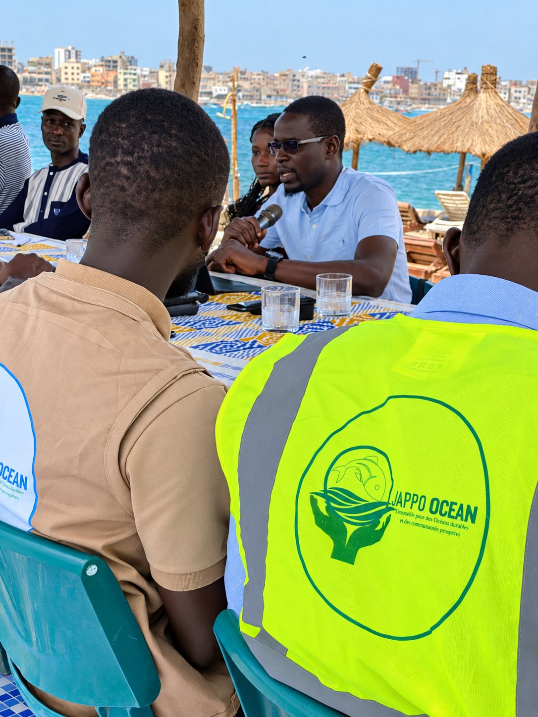 A man speaks into a microphone at a Jappo Ocean gathering by the sea